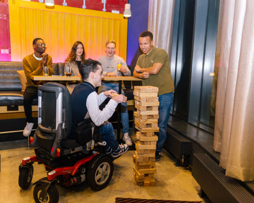 Young adults playing giant jenga in a bar setting